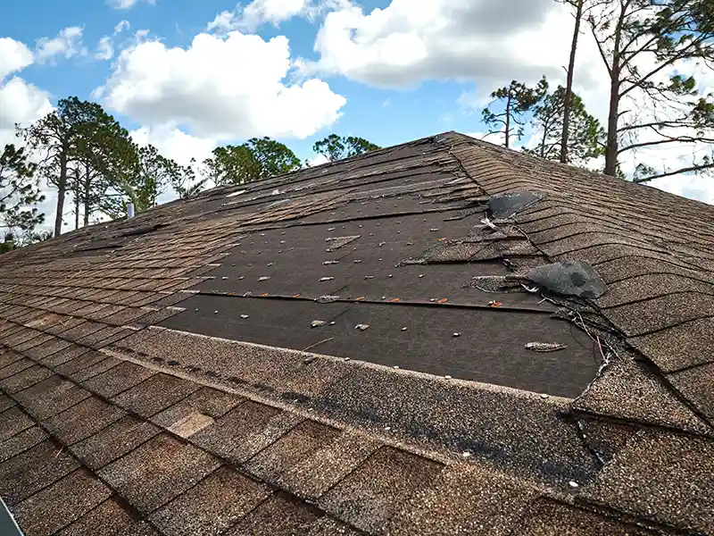 damaged house roof with missing asphalt shingles image
